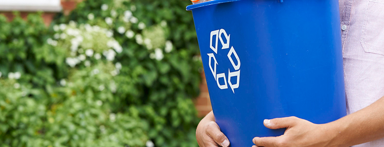 A person carrying a blue recycling bin.