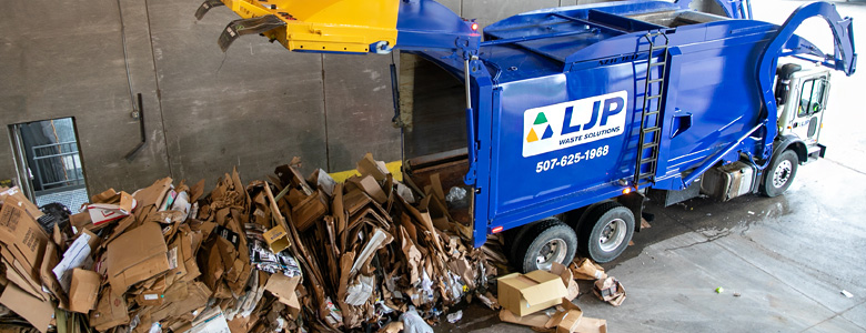 An LJP waste collection truck unloading recycled cardboard.